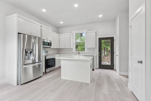 kitchen featuring sink, a center island, white cabinetry, light hardwood / wood-style floors, and stainless steel appliances