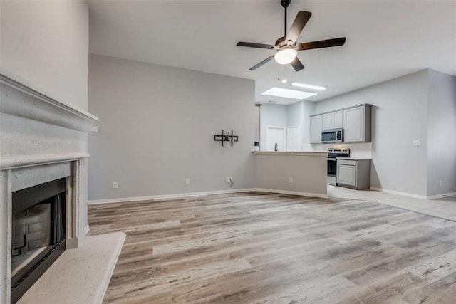 unfurnished living room with light hardwood / wood-style flooring, a high end fireplace, and ceiling fan