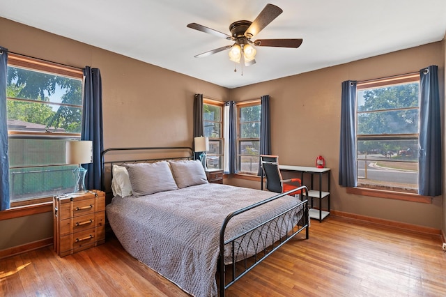 bedroom with ceiling fan, light hardwood / wood-style floors, and multiple windows