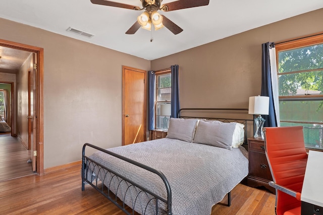 bedroom with ceiling fan, light wood-type flooring, and multiple windows