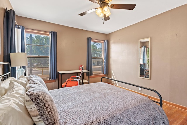 bedroom with ceiling fan, multiple windows, and hardwood / wood-style floors