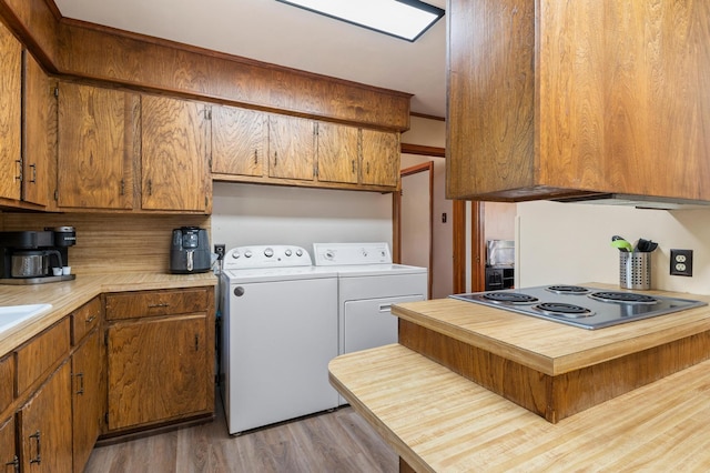 kitchen with light hardwood / wood-style flooring, stainless steel cooktop, tasteful backsplash, and washing machine and dryer