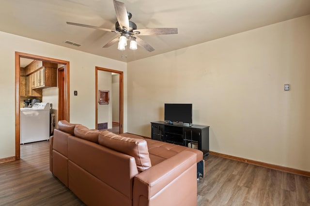 living room with wood-type flooring, washer and dryer, and ceiling fan