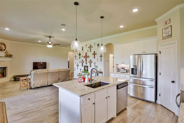 kitchen featuring ceiling fan, appliances with stainless steel finishes, white cabinetry, and a tile fireplace