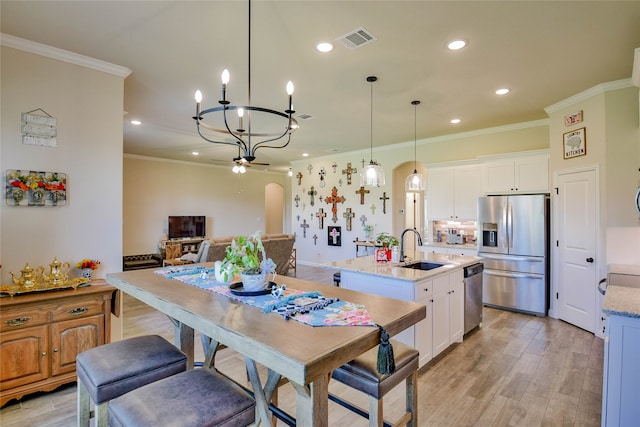 kitchen featuring white cabinets, an island with sink, sink, appliances with stainless steel finishes, and light stone countertops