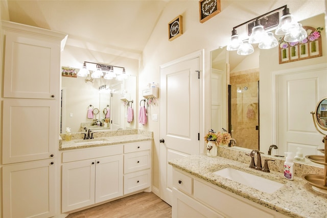 bathroom with wood-type flooring, vanity, lofted ceiling, and a shower with door