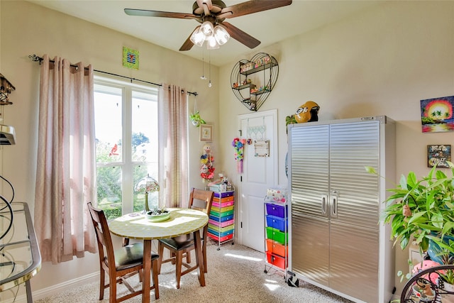 dining space with ceiling fan and light carpet