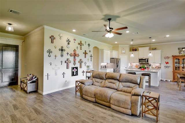 living room with light hardwood / wood-style floors, ceiling fan, and crown molding