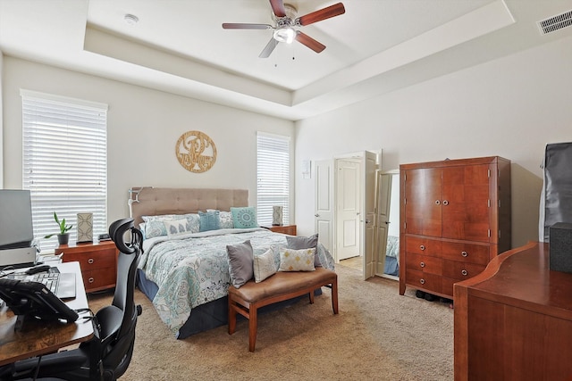 bedroom with ceiling fan, a raised ceiling, and multiple windows