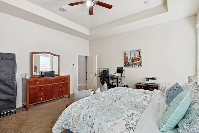 carpeted bedroom featuring a tray ceiling and ceiling fan