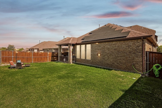 back house at dusk featuring a lawn