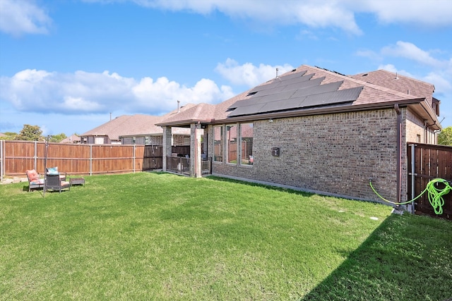 rear view of house with solar panels and a lawn