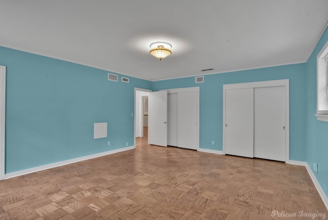 unfurnished bedroom featuring ornamental molding, multiple closets, and light parquet flooring