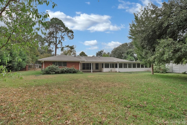 back of property with a lawn and a sunroom