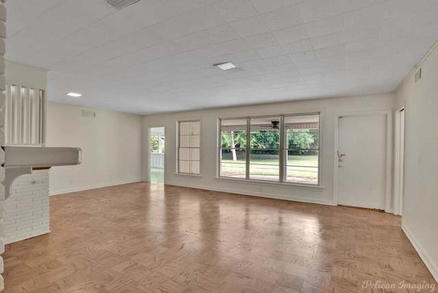 unfurnished living room featuring light parquet flooring and a brick fireplace