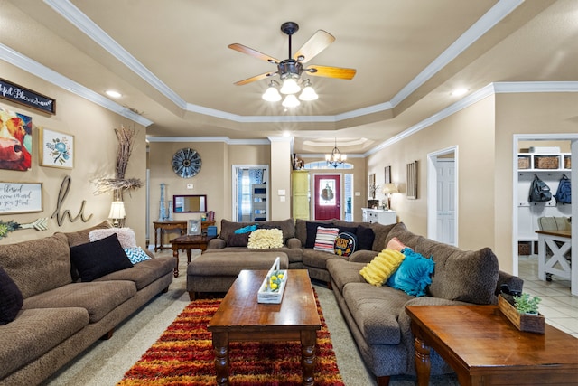 living room with crown molding, ceiling fan with notable chandelier, a tray ceiling, and ornate columns