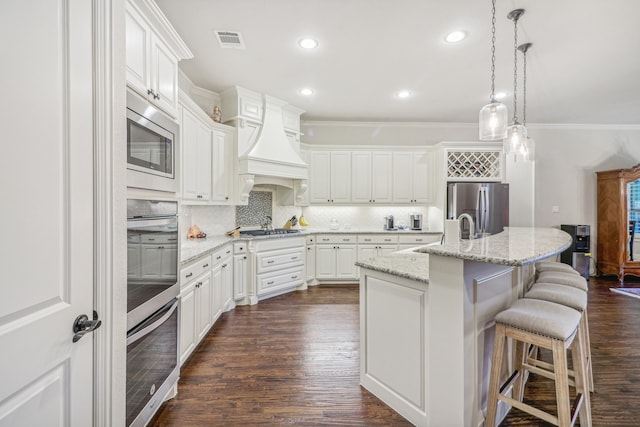 kitchen with white cabinetry, dark hardwood / wood-style flooring, an island with sink, a breakfast bar, and appliances with stainless steel finishes