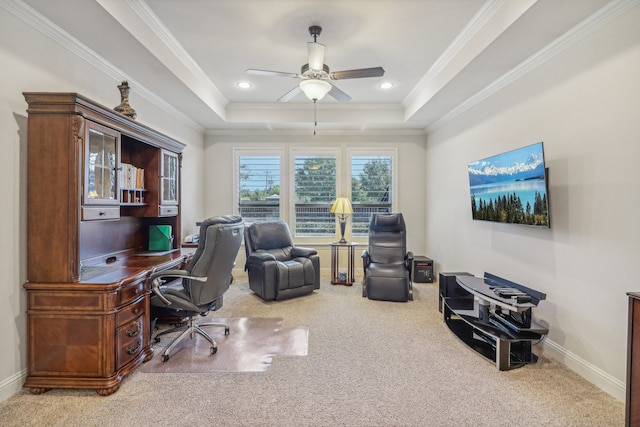 carpeted office with ceiling fan, ornamental molding, and a tray ceiling