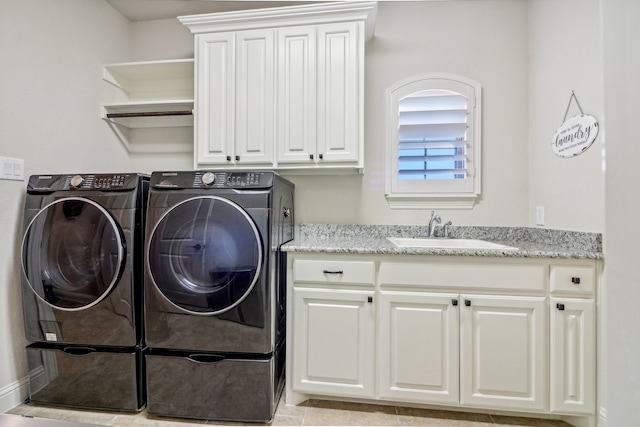 washroom with cabinets, light tile patterned floors, washing machine and dryer, and sink