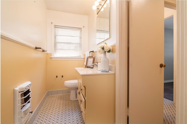 bathroom featuring vanity, heating unit, and toilet