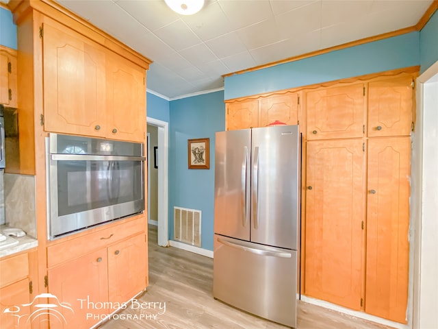 kitchen with crown molding, light brown cabinetry, stainless steel appliances, and light hardwood / wood-style floors