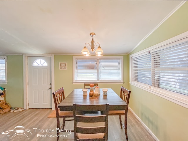 dining room featuring crown molding, a healthy amount of sunlight, a notable chandelier, and light wood-type flooring