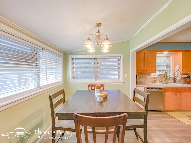 dining space with light wood-type flooring, crown molding, sink, a chandelier, and lofted ceiling