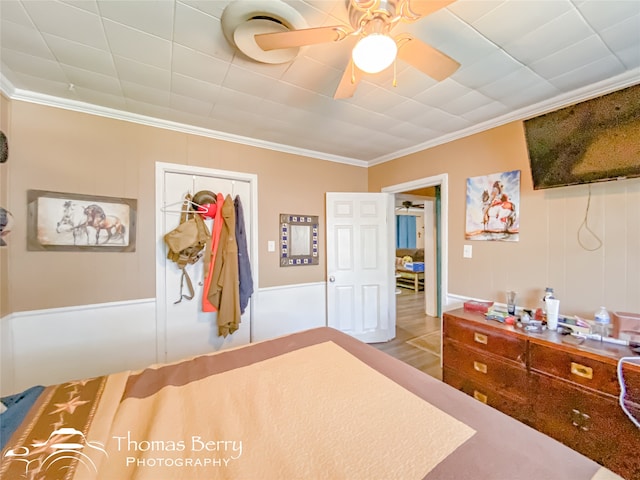 bedroom with hardwood / wood-style floors, a closet, ceiling fan, and crown molding