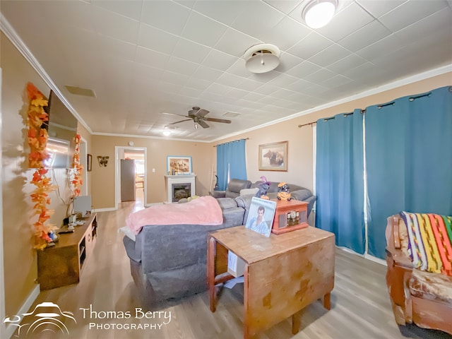 living room with hardwood / wood-style floors, ceiling fan, and crown molding