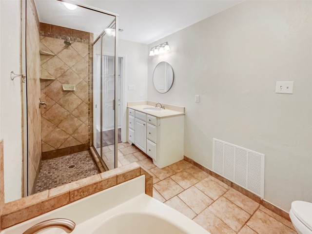 bathroom with a tile shower, vanity, toilet, and tile patterned floors