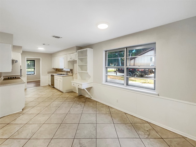 kitchen with white cabinetry, dishwasher, light tile patterned floors, range hood, and sink