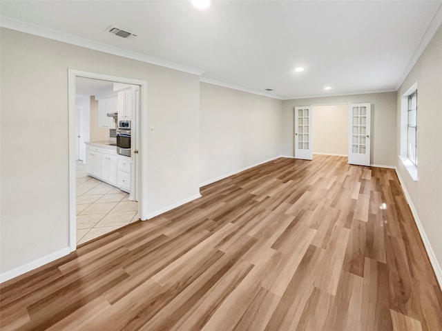 unfurnished room featuring light wood-type flooring, crown molding, and french doors