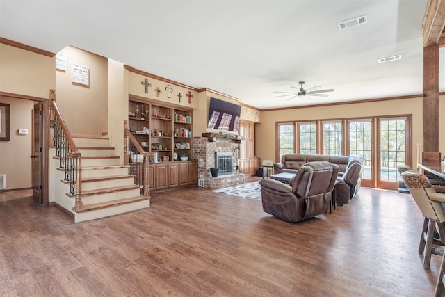 living room with ceiling fan, hardwood / wood-style flooring, a fireplace, and crown molding