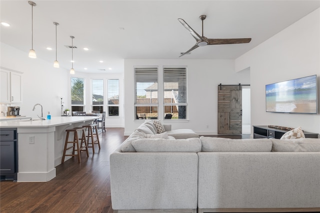 living room with dark hardwood / wood-style floors, a barn door, sink, and ceiling fan