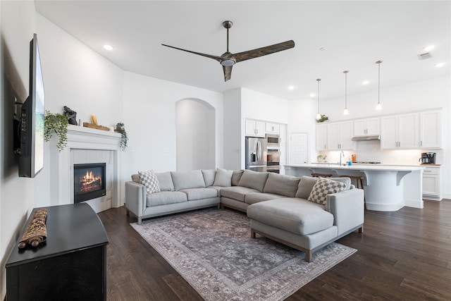 living room with dark hardwood / wood-style floors, ceiling fan, and a tile fireplace