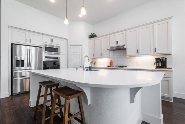 kitchen with appliances with stainless steel finishes, an island with sink, dark wood-type flooring, and sink