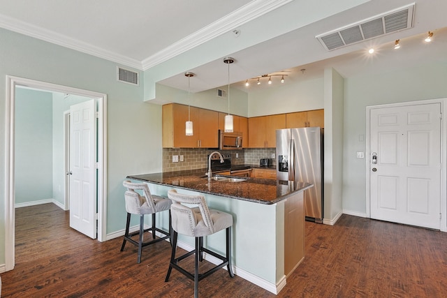 kitchen featuring kitchen peninsula, sink, pendant lighting, and appliances with stainless steel finishes