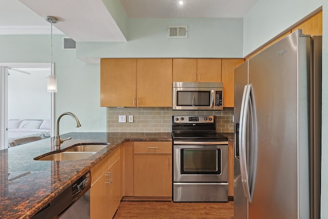 kitchen featuring sink, stainless steel appliances, light hardwood / wood-style flooring, dark stone counters, and decorative light fixtures