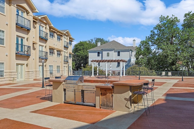 view of home's community featuring a pergola, area for grilling, and exterior bar