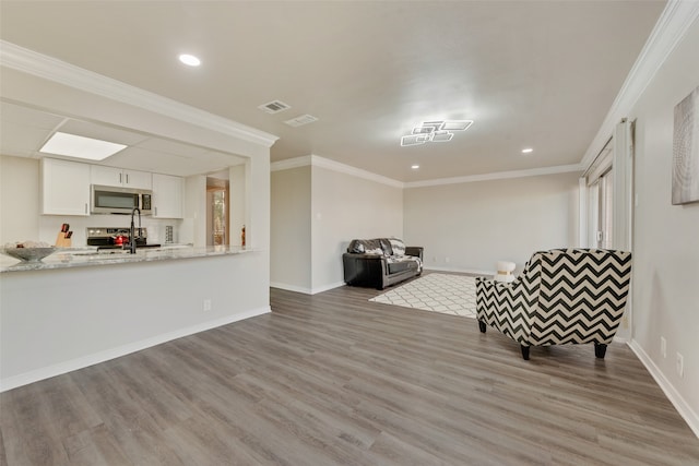 living area with a healthy amount of sunlight, light hardwood / wood-style floors, and ornamental molding