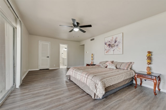 bedroom featuring crown molding, light hardwood / wood-style floors, ceiling fan, and ensuite bathroom