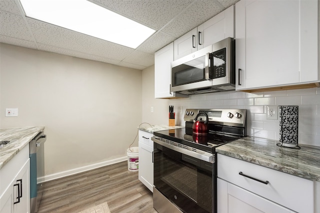 kitchen with a drop ceiling, white cabinetry, light hardwood / wood-style flooring, and stainless steel appliances