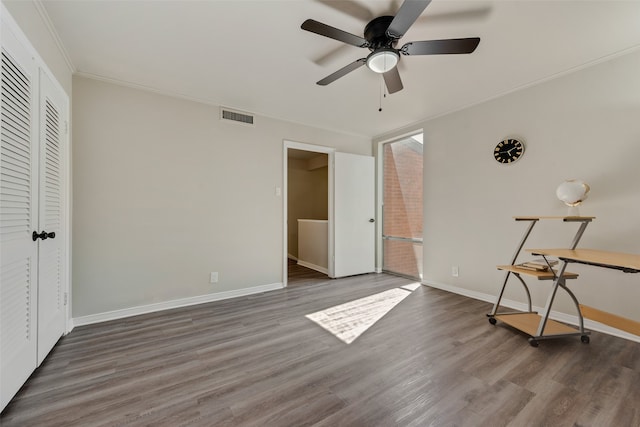 unfurnished bedroom with ornamental molding, ceiling fan, dark wood-type flooring, and a closet