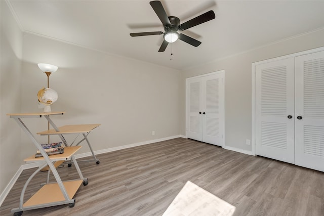 unfurnished office with light wood-type flooring, ornamental molding, and ceiling fan