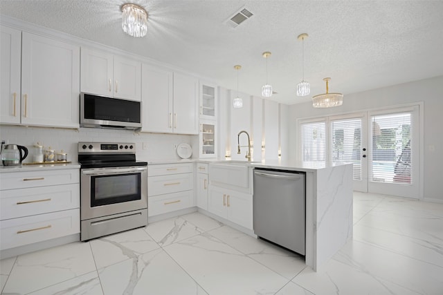 kitchen with decorative light fixtures, stainless steel appliances, and white cabinets