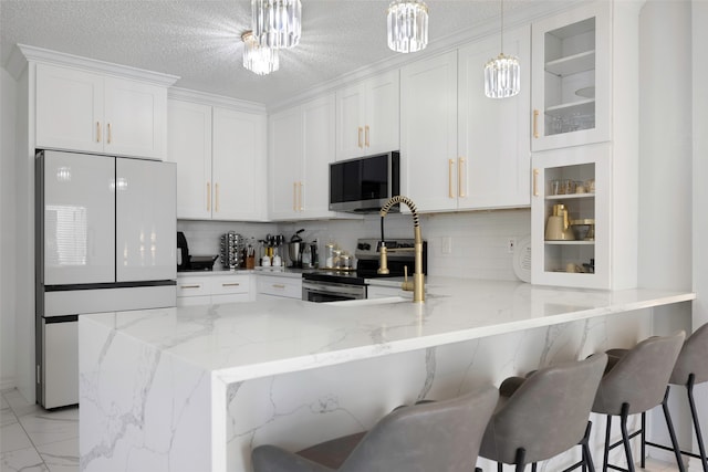 kitchen featuring white cabinetry, kitchen peninsula, a kitchen breakfast bar, stainless steel appliances, and an inviting chandelier