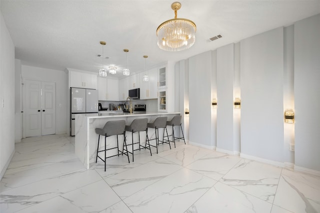 kitchen with pendant lighting, white cabinetry, white fridge, an inviting chandelier, and a kitchen breakfast bar