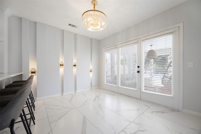 dining room featuring a chandelier, a textured ceiling, and french doors