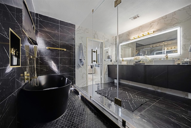 bathroom with vanity, tile walls, a textured ceiling, and plus walk in shower