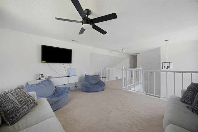 living room with ceiling fan, carpet floors, and a textured ceiling